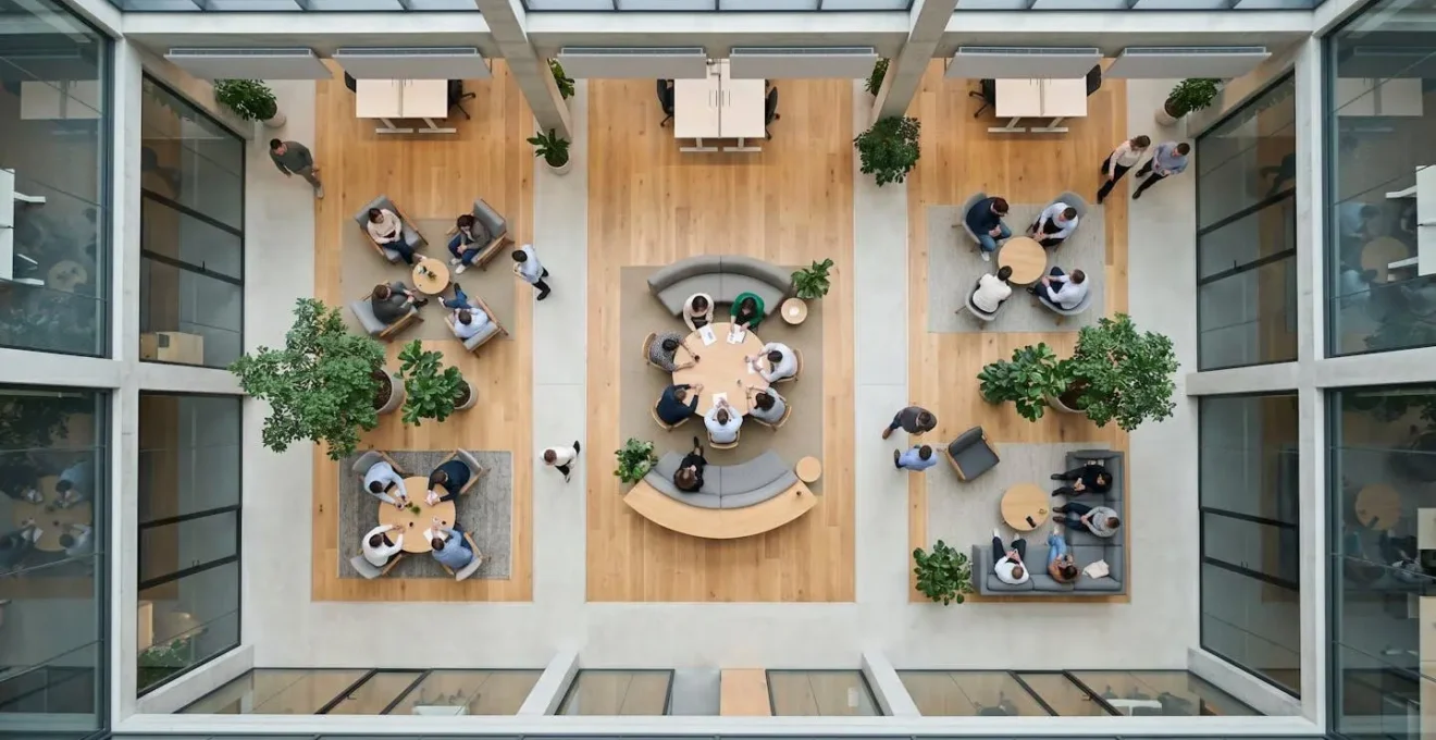 Vue aérienne minimaliste d'un open space moderne avec employés en réunion informelle