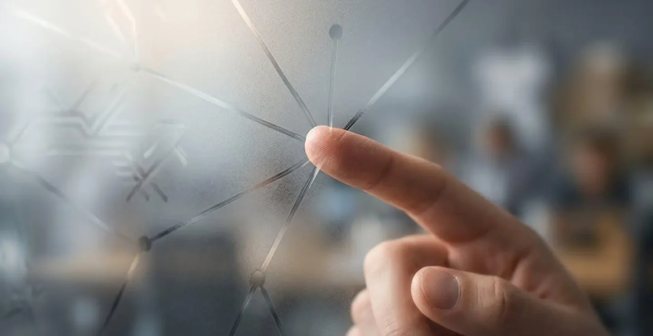 Vue macro d'une main traçant des connexions entre des points sur une surface de verre